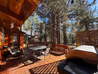 a deck with a grill and a table and chairs at Little Big Pine - Perfect, stylish cabin near the lake with a great deck in Big Bear Lake