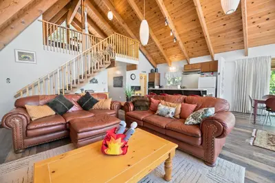 a living room with leather couches and a table at Moonlight Shores Lakefront - Lakefront home with hot tub! in Fawnskin