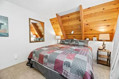 a bedroom with a large bed with a wooden headboard at Moonlight Shores Lakefront - Lakefront home with hot tub! in Fawnskin