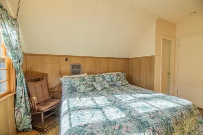 a bedroom with a bed and a chair at Rustic Pine - Rustic true log cabin with plenty of charm, Close to everything! in Big Bear Lake