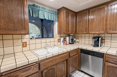 a kitchen with wooden cabinets and a sink and a window at Snow Summit Getaway - Walk to Snow Summit Ski Resort in Big Bear Lake