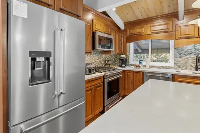 a kitchen with wooden cabinets and a stainless steel refrigerator at Snow Summit Thrush8 - Walk to Snow Summit Ski Resort in Big Bear Lake