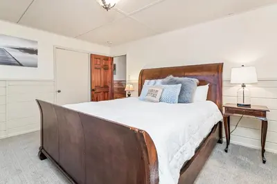 a bedroom with a large bed with a wooden headboard at Stillwater Cove Lakefront - Breathtaking views, charming vintage cabin, woodsy interior! Boat Dock! in Big Bear Lake