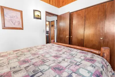 a bedroom with a bed and a wooden cabinet at The Cuddle Inn - True feeling of a great cabin! Beautiful and homey! Walking distance to the lake! in Big Bear Lake