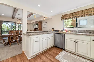 a kitchen with white cabinets and a dining room at Whiskey Pines Chalet - Warm and cozy cabin with modern features made more fun with a gameroom in Big Bear Lake