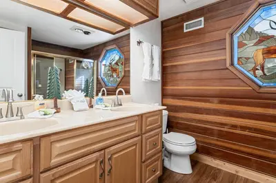 a bathroom with wooden walls and a toilet and a sink at Whiskey Pines Chalet - Warm and cozy cabin with modern features made more fun with a gameroom in Big Bear Lake
