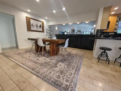 a dining room with a table and chairs on a rug at Stylish 4 Bedroom Home Near Venice Beach with Backyard BBQ in Los Angeles