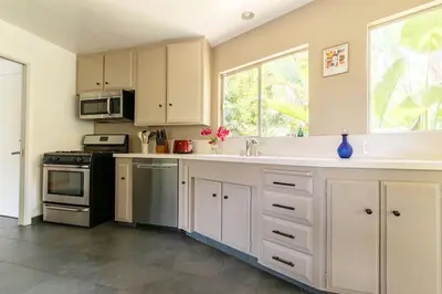 a kitchen with white cabinets and a sink and a stove at Stunning Hollywood Midcentury Modern-Views-Best Location! in Los Angeles