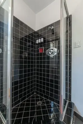 a black tiled shower with a glass door at Stunning Hollywood Midcentury Modern-Views-Best Location! in Los Angeles
