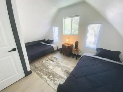 a bedroom with two beds and a room with a door at The Inspo Cabin with Stunning View in Running Springs