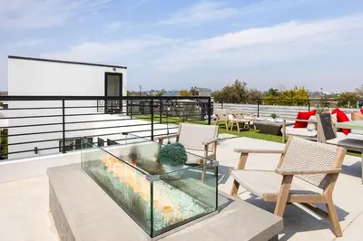 a patio with a glass table and chairs on a roof at The Palms Pad - 5 Min from Beach - Golf,Arcade,Sauna in Los Angeles