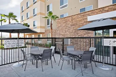 a patio with tables and chairs and umbrellas at Fairfield by Marriott Inn & Suites Chino in Chino