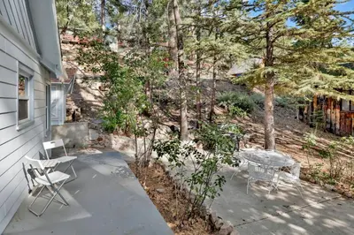 a patio with a table and chairs next to a house at Pinglewood Cabin- Furnished Fawnskin Group Retreat in Fawnskin