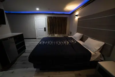a bedroom with a black bed with a blue light at Artesia Motor Inn in Bellflower