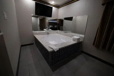 a bathroom with a large tub with a large mirror at Artesia Motor Inn in Bellflower