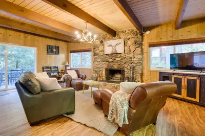 a living room with leather furniture and a stone fireplace at Steps to Lake Arrowhead Cabin with Full Lake Access in Lake Arrowhead