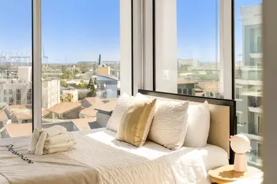 a bed with white pillows in front of a large window at #Marbella Lane - Panoramic Delight Dream Escape! in Long Beach