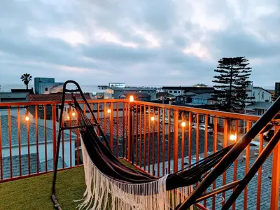 a hammock on a balcony next to the water at Ocean View Hot Tub Luxe House Steps to Sand in Hermosa Beach