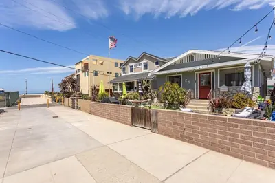 a house with a brick wall next to a sidewalk at Hermosa Bungalow 1920s Charm Steps to the Strand in Hermosa Beach