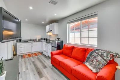 a living room with a red couch and a kitchen at Sleek San Fernando Studio about 14 Mi to Universal in San Fernando