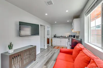 a living room with a red couch and a kitchen at Sleek San Fernando Studio about 14 Mi to Universal in San Fernando