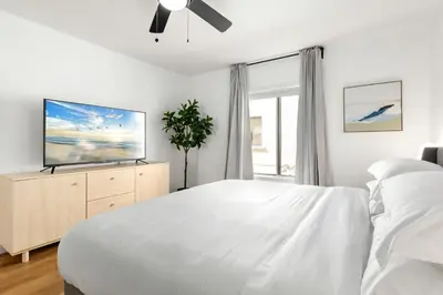 a white bedroom with a large bed and a tv at Double King Suite with Patio Dining and Parking NRP21-00386 in Long Beach