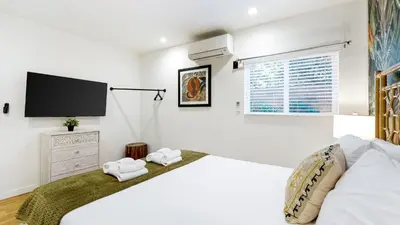 a white bedroom with a large bed and a flat screen tv at Urban Jungle by AvantStay in Los Angeles