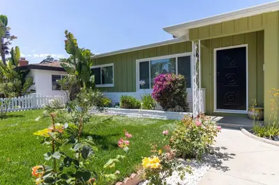 a green house with flowers in the yard at Villa La Verde - Newly Designed 4BR Villa with Pool & Guesthouse by Topanga in Los Angeles
