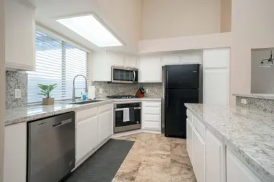 a kitchen with white cabinets and a black refrigerator at Families/Digital Nomads/Corporate Housing in Bakersfield