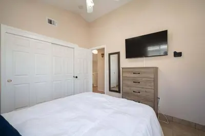 a bedroom with a white bed and a flat screen tv at Families/Digital Nomads/Corporate Housing in Bakersfield