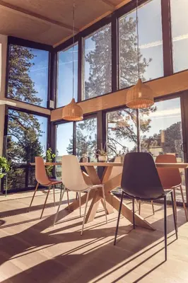 a dining room with chairs and a table and windows at Spectacular Designer Treehouse with Mountain Views in Pine Mountain Club