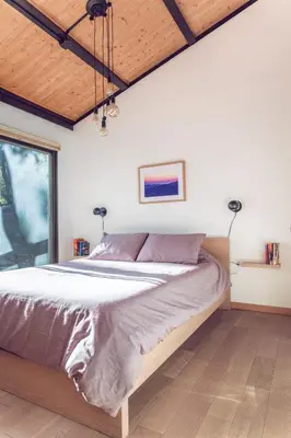 a bedroom with a bed with white walls and wood floors at Spectacular Designer Treehouse with Mountain Views in Pine Mountain Club