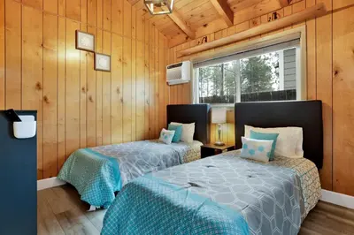 two beds in a room with wooden walls at Sweet Retreat 1- Cozy Relaxing Resort Cabin in Big Bear Lake