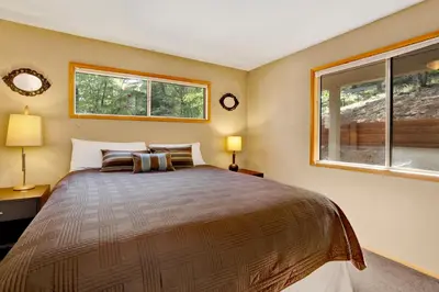 a bedroom with a large bed with two windows at Knickerbocker Retreat- Hot Tub- Game Tables in Big Bear Lake