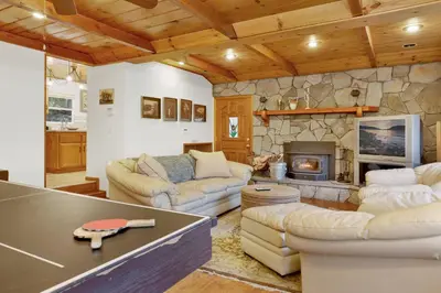 a living room with couches and a stone fireplace at Knickerbocker Retreat- Hot Tub- Game Tables in Big Bear Lake