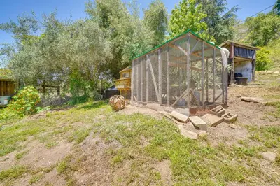 a greenhouse in a field next to a house at Farmhouse-Chic Carpinteria Cottage with Pool Access in Carpinteria
