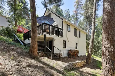 a house with a balcony in the woods at Twin Peaks Vacation Rental with Hot Tub! in Twin Peaks