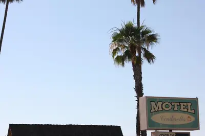 a motel sign with a palm tree in the background at Cinderella Motel in Wasco