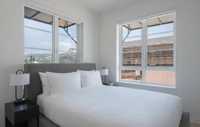 a bedroom with a white bed and two windows at Level Hollywood in Los Angeles