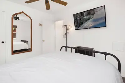 a white bedroom with a bed and a mirror at Maltby Modern Log Cabin Relaxing Chalet Retreat in Big Bear Lake