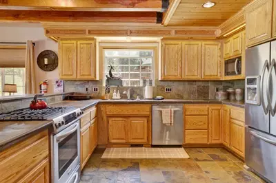 a kitchen with wooden cabinets and stainless steel appliances at Lakefront Village Castle- Foosball- Boat Dock- in Big Bear Lake