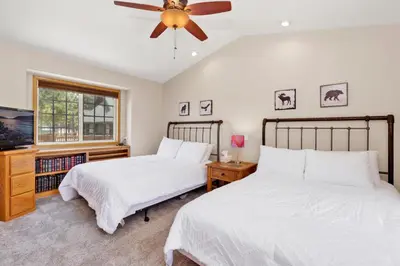 two beds in a bedroom with a ceiling fan at Lakefront Village Castle- Foosball- Boat Dock- in Big Bear Lake