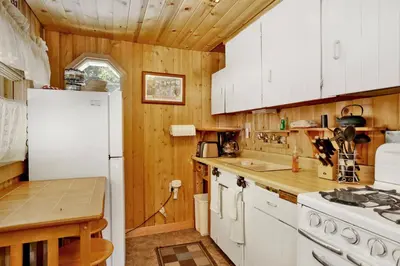 a kitchen with wooden walls and a white refrigerator at Moonridge R n R- Cozy Single Level Central Chalet Home in Big Bear Lake