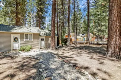 a home in the woods with a fence and trees at Moonridge R n R- Cozy Single Level Central Chalet Home in Big Bear Lake