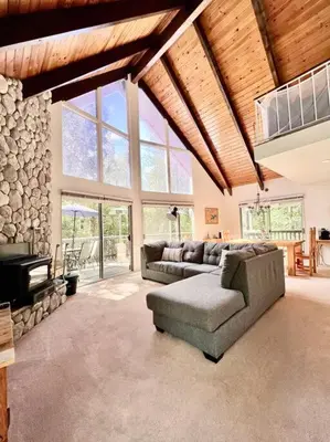 a living room with a couch and a stone wall at Family Friendly A Frame, Pets stay Free! in Lake Arrowhead