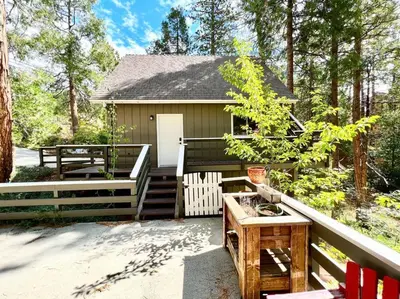 a small cabin with a porch and a wooden table at Family Friendly A Frame, Pets stay Free! in Lake Arrowhead