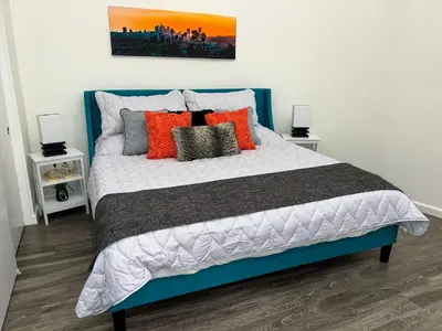 a bedroom with a large bed with orange and grey pillows at Downtown Los Angeles Skyline balcony view Modern Penthouse in Los Angeles