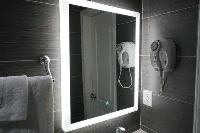 a mirror in a bathroom with a phone on the wall at Avenue Motel in Gardena