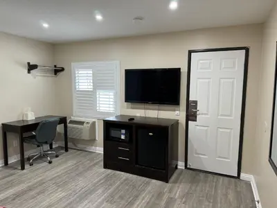 a room with a desk and a television and a door at Avenue Motel in Gardena