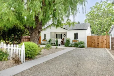 a white house with a fence and a tree at Retro Cottage, Hot Tub, Putting Green, walk to all in Thousand Oaks
